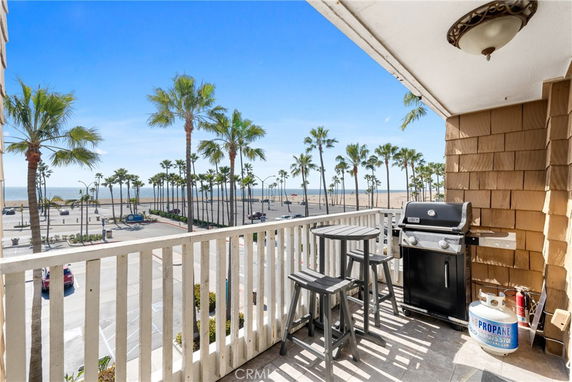 View from a balcony overlooking palm trees, a parking area, and the beach.