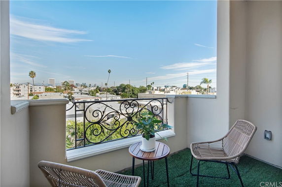 Balcony with chairs overlooking rooftops and cityscape.