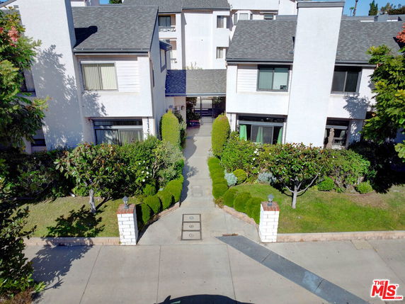 Front view of a multi-story residential building with a walkway and landscaped entrance.
