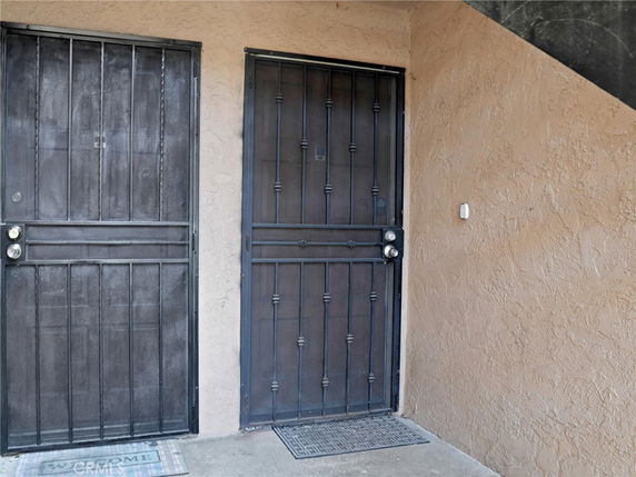 Entrance with metal security doors on a textured exterior wall.
