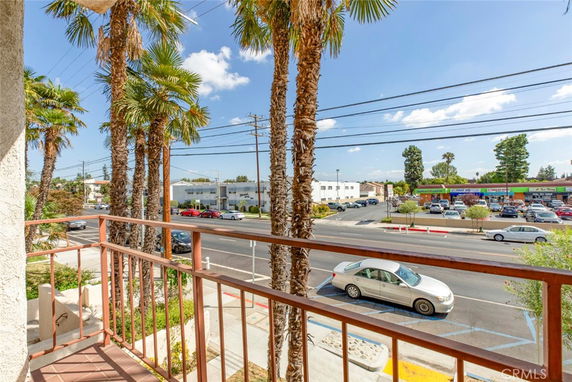 View from a balcony overlooking a street with cars and nearby commercial buildings.