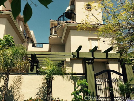 Front view of a multi-story house with decorative balconies and a gated entrance.