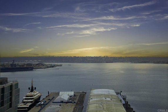 Panoramic view of a harbor with ships and buildings at sunset.
