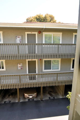 Front view of a two-story apartment building with covered parking spaces below.