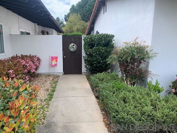 Front view of a house with a white exterior wall and wooden gate with a circular window.