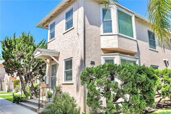 Corner view of a two-story house with stucco exterior and multiple windows.