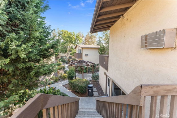 View of a two-story building from a staircase, with a patio area and surrounding greenery.