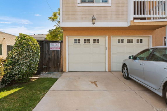 Driveway with a parked car and double garage doors.