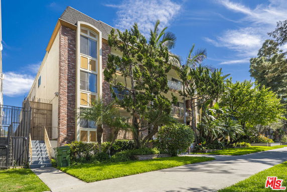 Front view of a multi-story residential building with a brick facade and outdoor balconies.