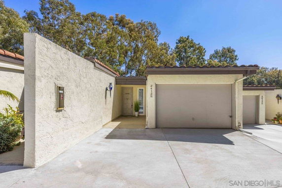 Front view of a single-story house with a garage and stucco walls.