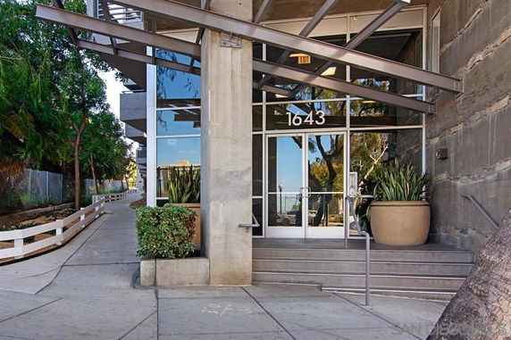 Front entrance of a modern building with glass doors and metal awning.