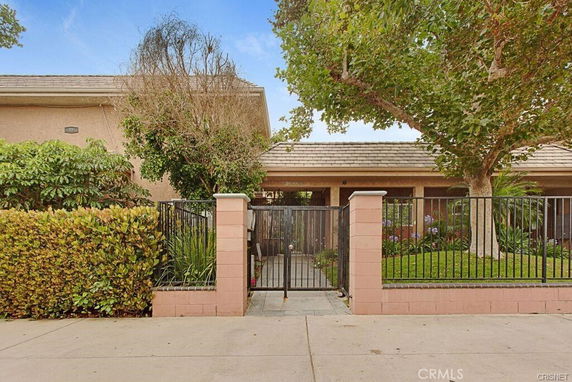 Front view of a single-story house with a metal gate and brick pillars.