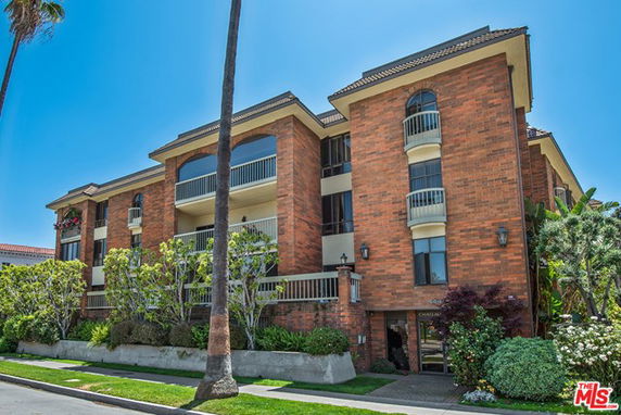 Front view of a multi-story brick apartment building with balconies.