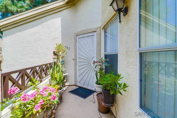 Front view of a house entrance with potted plants and a decorative white door.