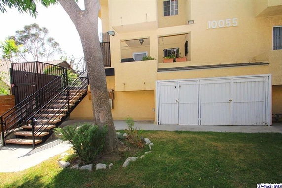 Front view of a building with an outdoor staircase leading to an upper level and a garage below.