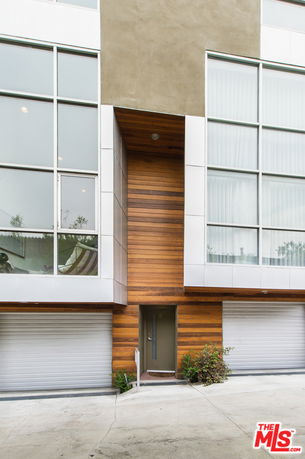 Front view of a modern multi-story building with large glass windows and wooden paneling.