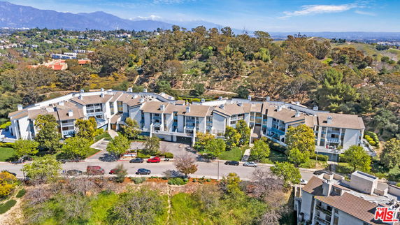Aerial view of a large residential complex with surrounding landscapes and hills.