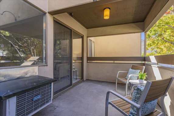 Patio area with chairs and a sliding glass door entrance.