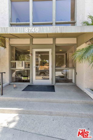 Front view of a building entrance with glass door and windows.