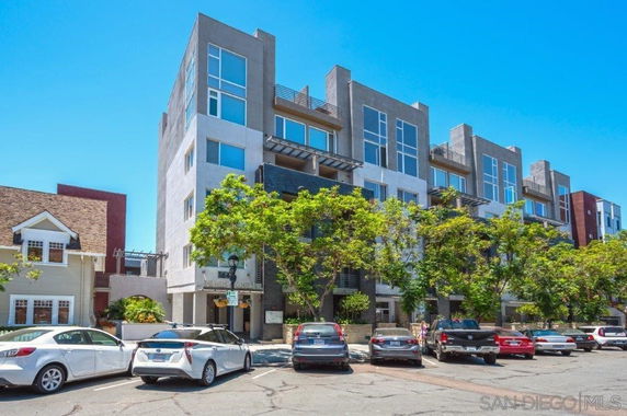 Front view of a multi-story apartment building with large windows and balconies.