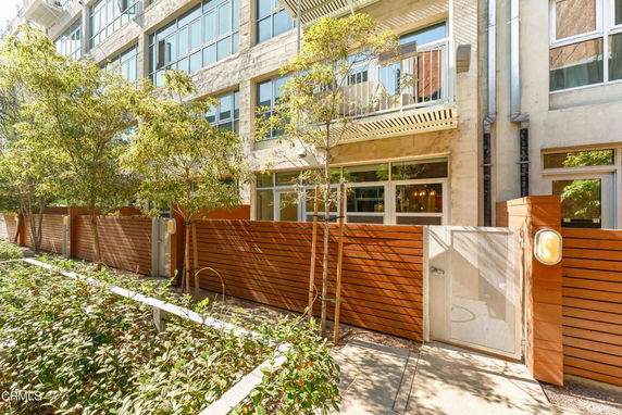 Front view of a multi-story building with a wooden fence and gate.