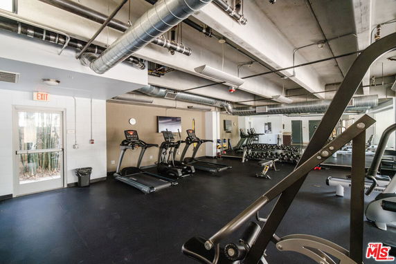 Interior view of a gym with fitness equipment and large windows.