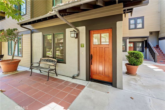 Front view of a house entrance with a wooden door and adjacent bench.