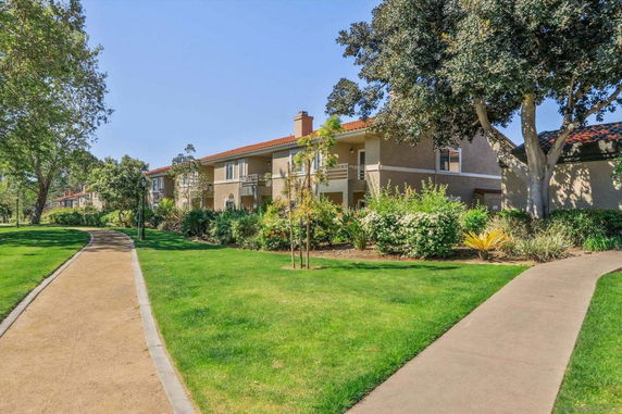 Side view of a two-story residential building with nearby pathways and greenery.