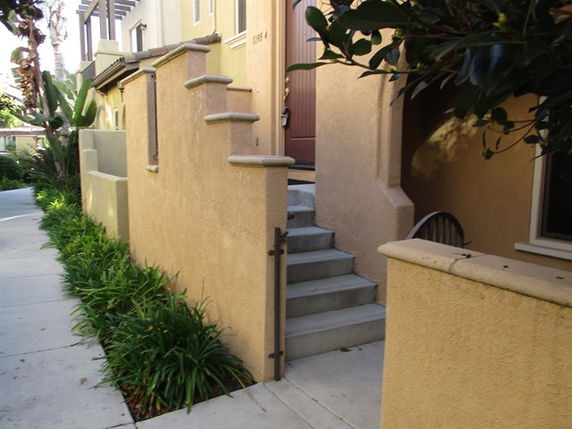 Front view of a multi-story building entrance with stairs and garden.