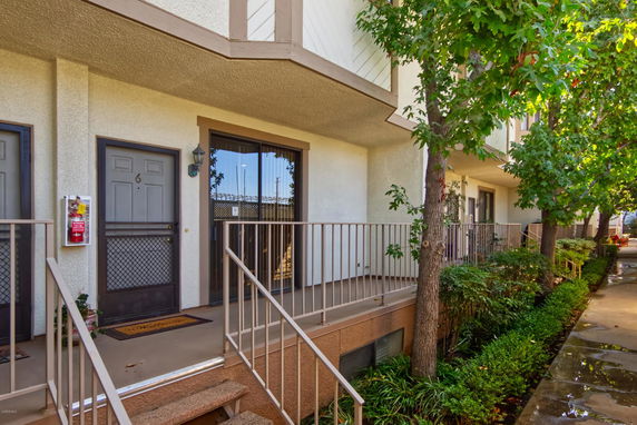 Front view of a multi-story townhouse with stairs leading to a raised entrance.