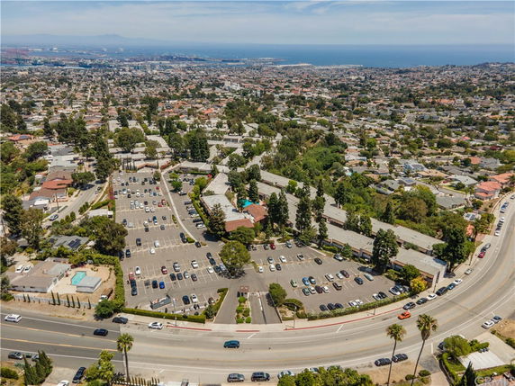 Panoramic view of a residential area with roads and parking lots, overlooking a coastal cityscape.