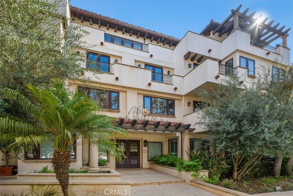 Front view of a multi-story residential building with balconies and a covered entryway.