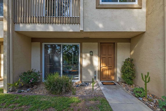 Front view of a two-story house with a sliding glass door and a single wooden entrance door.
