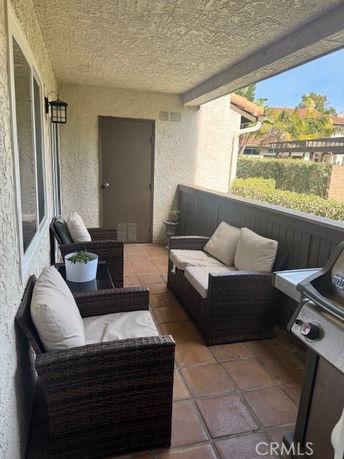 Outdoor patio area with seating and a grill, adjacent to a house.