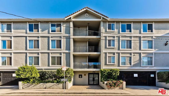 Front view of a multi-story residential building with balconies and a symmetrical window arrangement.