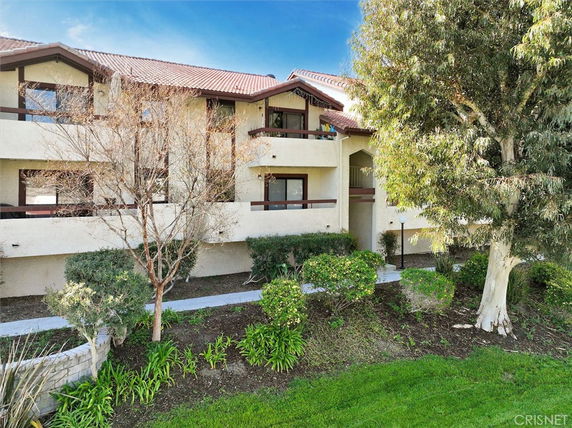 Front view of a two-story residential building with balconies and a tiled roof.