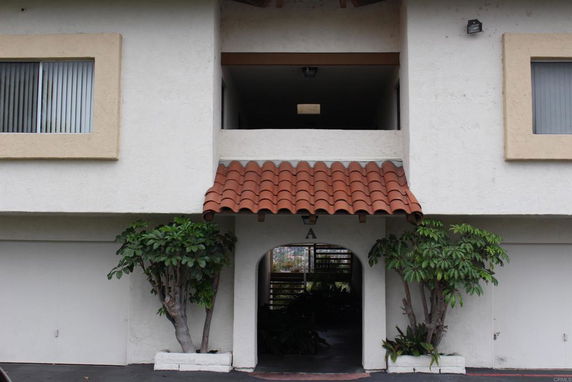 Front view of a building with a tiled roof entrance and two windows.