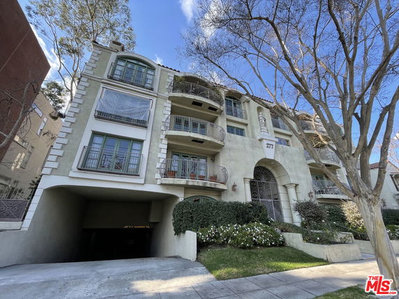 Front view of a multi-story building with balconies and a gated entrance.