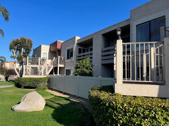 Front view of a two-story building with balconies and a fenced yard.