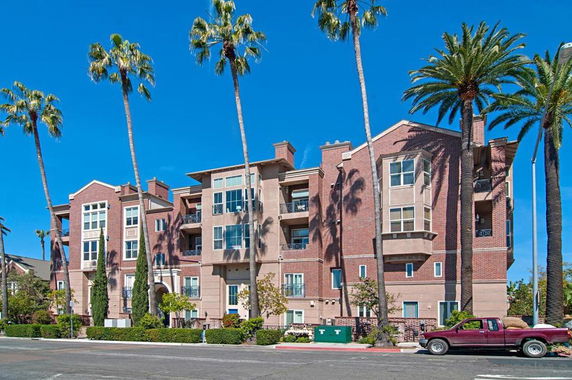 Front view of a multi-story residential building with red brick and beige stucco exterior.