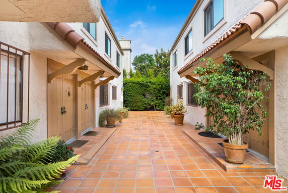Front view of residential buildings with tiled walkway and potted plants.