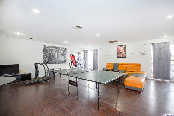 Room with a table tennis setup, exercise equipment, and an orange couch.