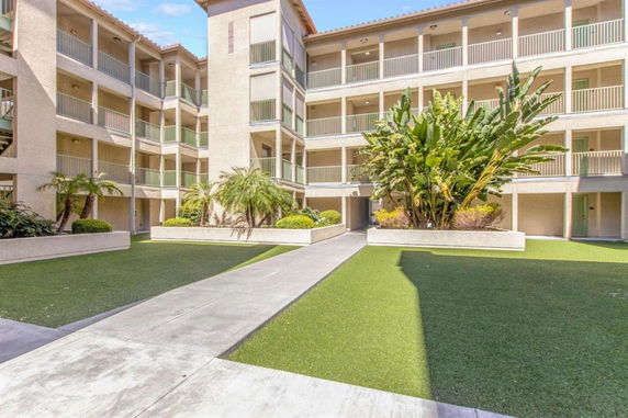Front view of a multi-story building with balconies and landscaped courtyard.