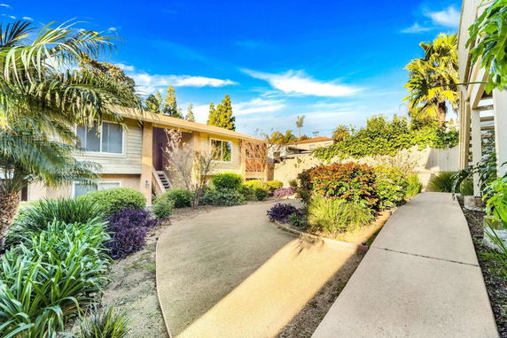 View of a house with a landscaped garden and a path leading to it.