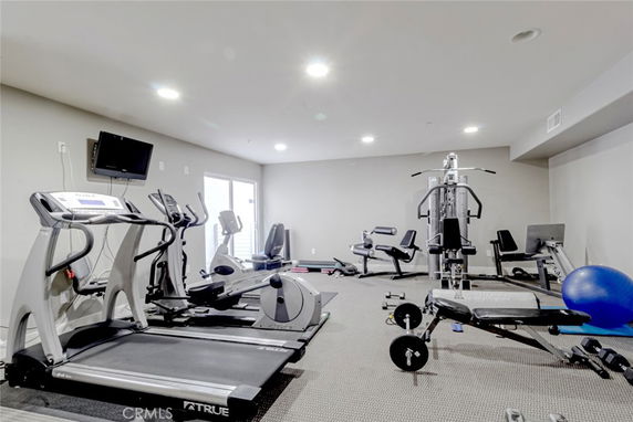 Indoor gym with various exercise equipment including treadmills, ellipticals, and weight machines.