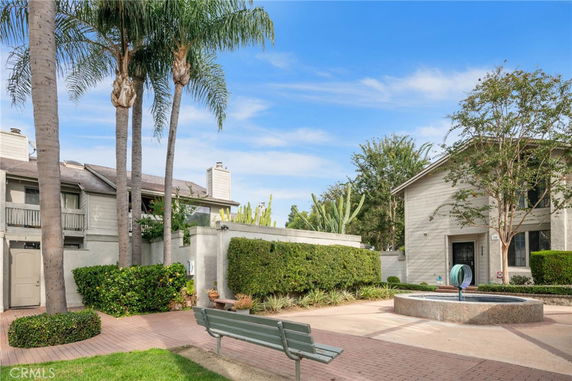 Front view of a residential building with surrounding greenery and paved area.