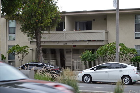 Front view of a two-story building with a balcony and gated entrance.