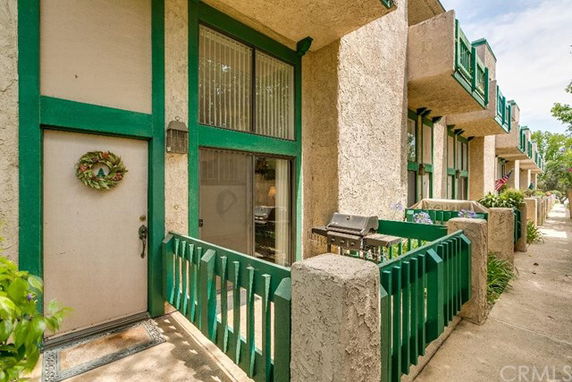Front view of a townhouse with green trim and a small patio area.