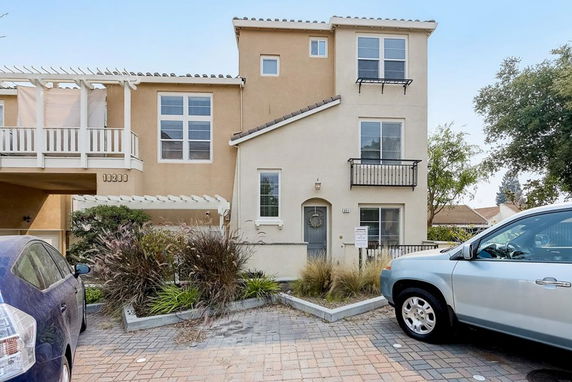 Front view of a multi-story house with a parking area and balconies.