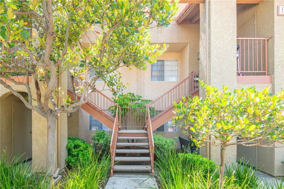 Front view of a multi-story residential building with external staircase and greenery.